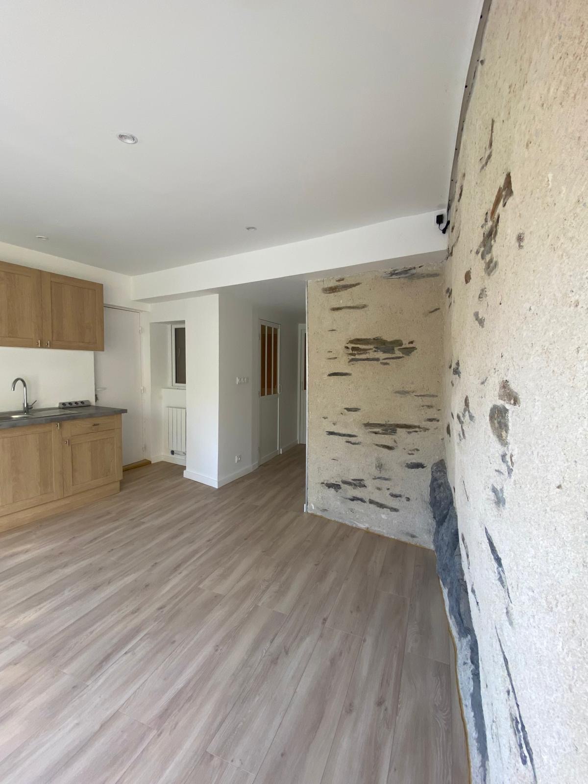 Pièce de vie du projet Loft à Angers après travaux, cuisine bois et mur en pierre conservé