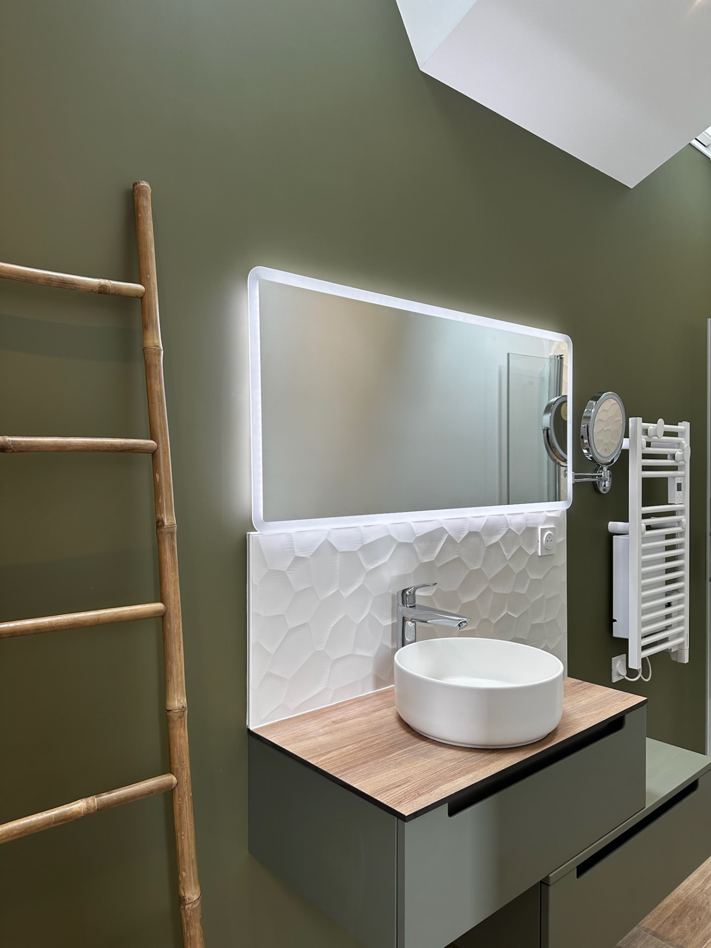 Salle de bain rénovée avec mur vert, vasque à poser et miroir lumineux